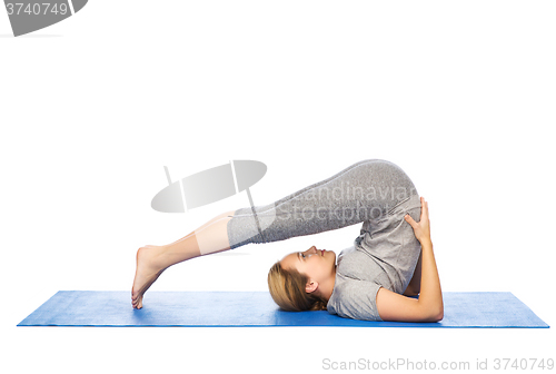 Image of woman making yoga in plow pose on mat