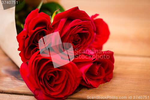 Image of close up of red roses bunch wrapped into paper