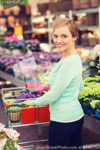 Image of happy woman with shopping trollye buying flowers