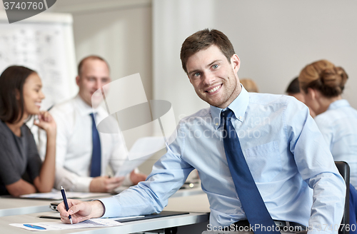 Image of group of smiling businesspeople meeting in office