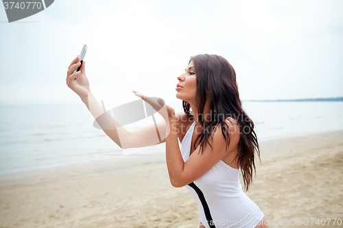 Image of young woman taking selfie with smartphone