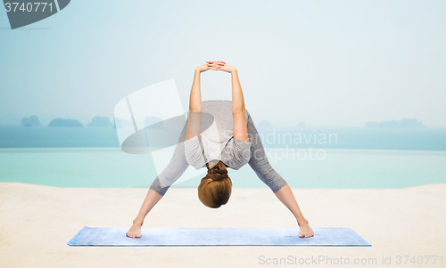 Image of woman making yoga wide-legged forward bend on mat