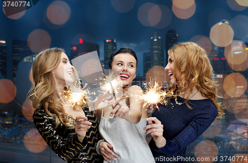 Image of happy young women with sparklers over night city