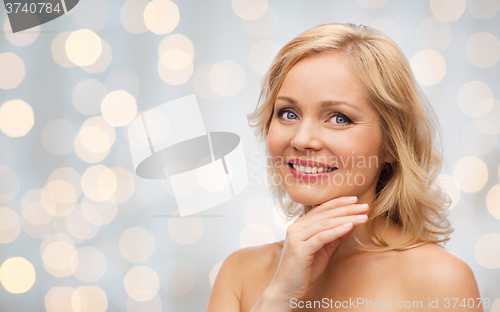 Image of smiling woman with bare shoulders touching face