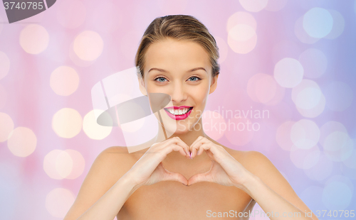 Image of smiling young woman showing heart shape hand sign