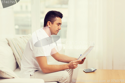 Image of man with papers and calculator at home