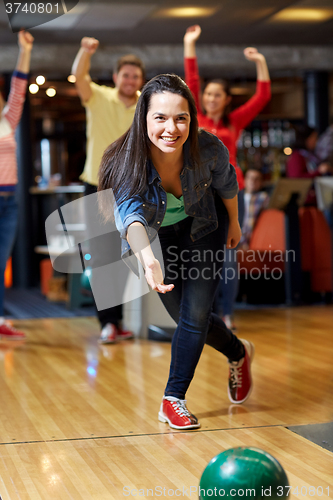 Image of happy young woman throwing ball in bowling club