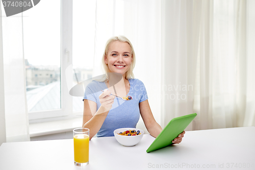 Image of woman with tablet pc eating breakfast at home