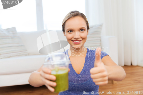 Image of happy woman with cup of smoothie showing thumbs up