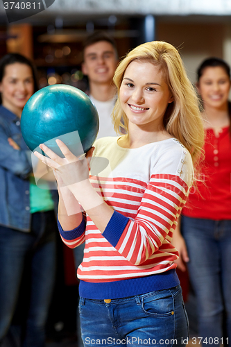 Image of happy young woman holding ball in bowling club