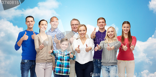 Image of happy people showing thumbs up over sky and clouds