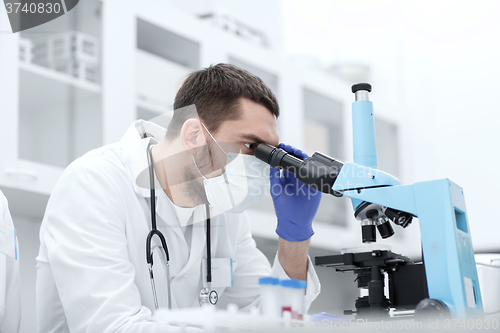 Image of young scientist looking to microscope in lab