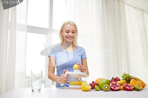 Image of smiling woman squeezing fruit juice at home