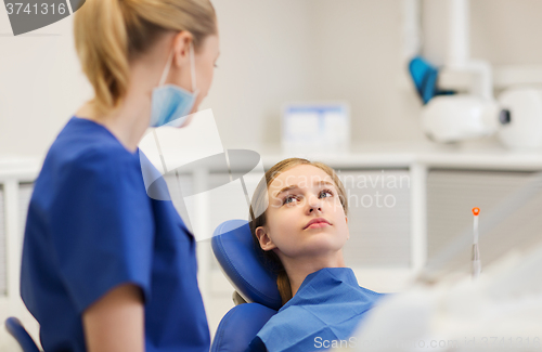 Image of happy female dentist with patient girl at clinic