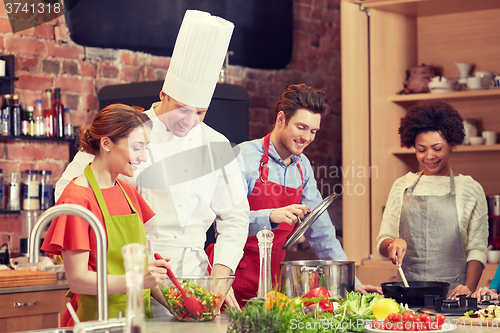 Image of happy friends and chef cook cooking in kitchen