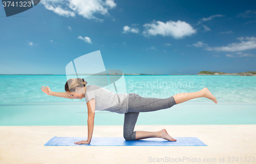 Image of woman making yoga in balancing table pose on mat