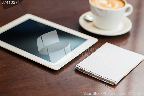 Image of close up of notebook with tablet pc and coffee