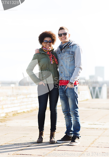 Image of happy teenage friends in shades hugging outdoors