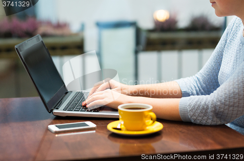 Image of close up of woman typing on laptop with coffee