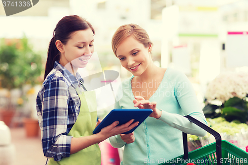 Image of happy women with tablet pc in greenhouse