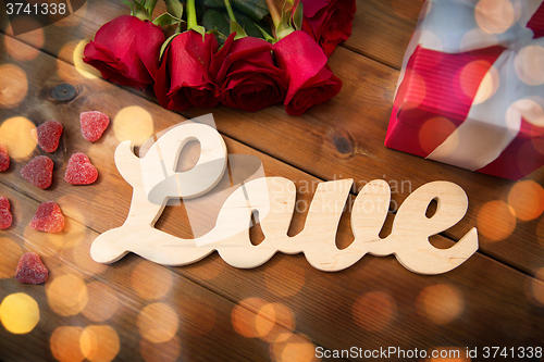 Image of close up of word love, red roses and gift box
