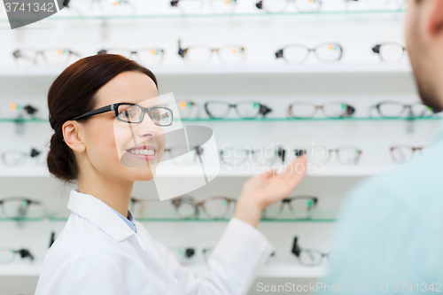 Image of optician showing glasses to man at optics store