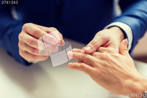 Image of close up of male gay couple hands and wedding ring