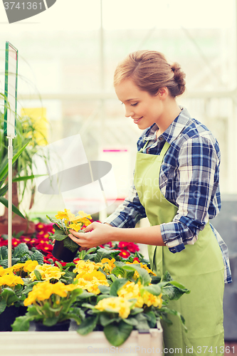 Image of happy woman holding flowers in greenhouse