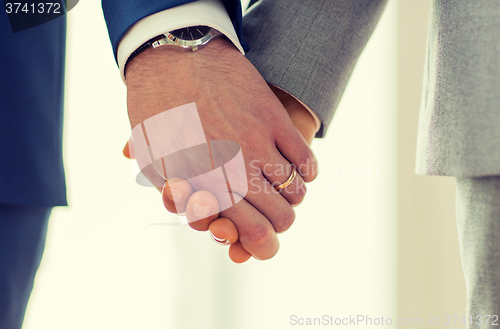 Image of close up of male gay hands with wedding rings on