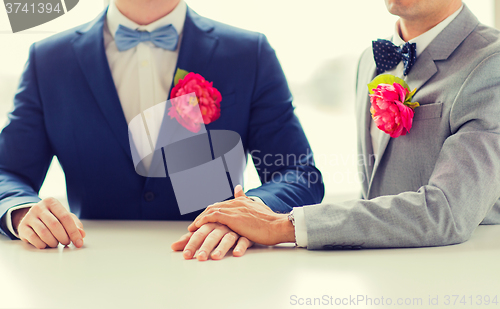 Image of close up of happy male gay couple holding hands