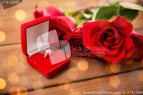 Image of close up of diamond engagement ring and red roses