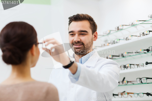 Image of optician putting glasses to woman at optics store