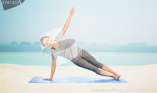 Image of woman making yoga in side plank pose on mat