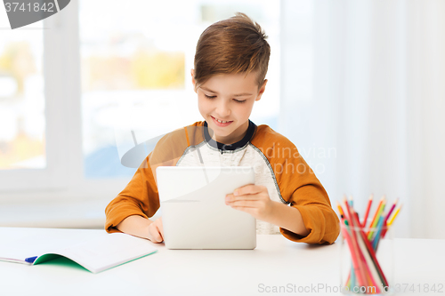 Image of smiling boy with tablet pc and notebook at home