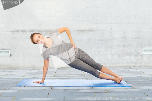 Image of woman making yoga in side plank pose on mat