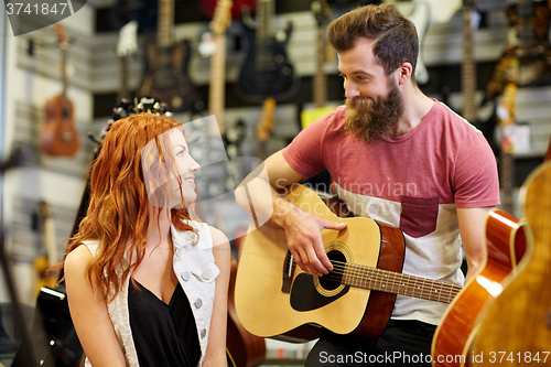 Image of couple of musicians with guitar at music store