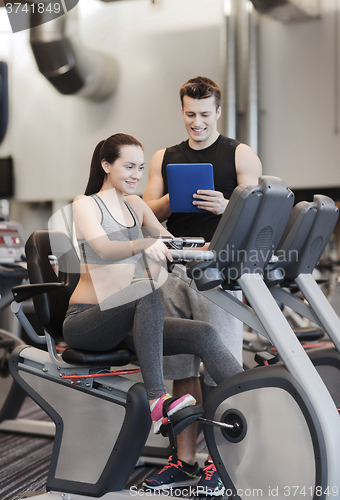 Image of happy woman with trainer on exercise bike in gym