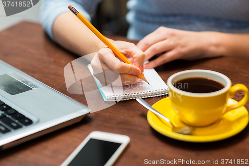 Image of close up of woman writing to notebook with pencil