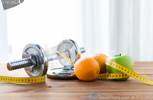 Image of close up of dumbbell, fruits and measuring tape