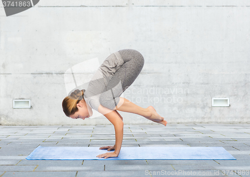 Image of woman making yoga in crane pose on mat