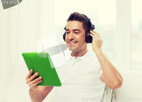 Image of smiling man with tablet pc and headphones at home