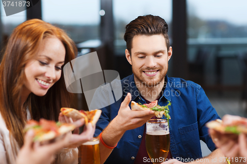 Image of friends eating pizza with beer at restaurant