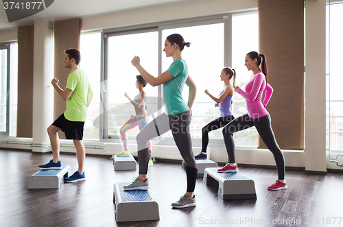 Image of group of people working out with steppers in gym