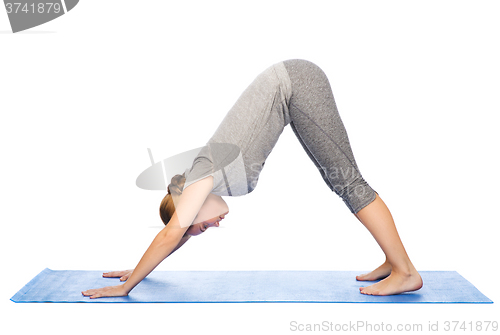 Image of woman making yoga dog pose on mat