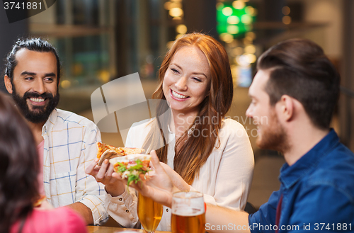 Image of friends eating pizza with beer at restaurant