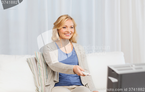 Image of woman with remote control switching tv at home