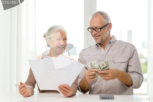 Image of senior couple with money and calculator at home