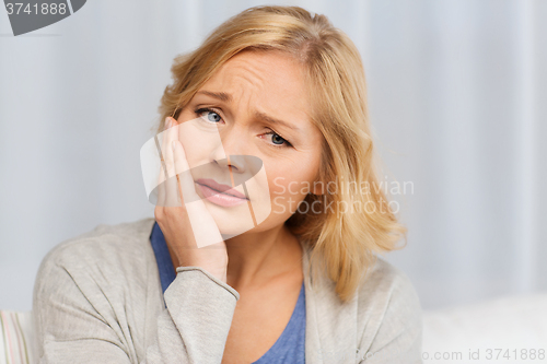 Image of unhappy woman suffering toothache at home