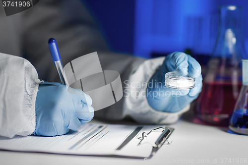 Image of close up of scientist writing test results in lab