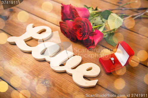 Image of close up of diamond ring, red roses and word love